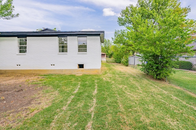 rear view of house featuring crawl space, brick siding, fence, and a yard