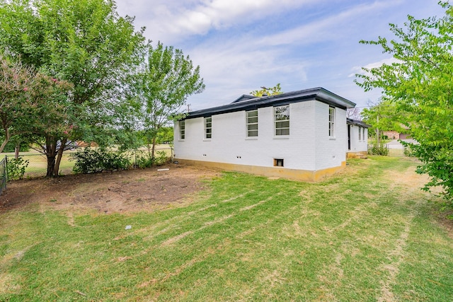 back of house featuring a yard, brick siding, and fence