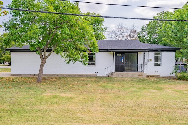 rear view of property featuring roof with shingles, brick siding, and a lawn