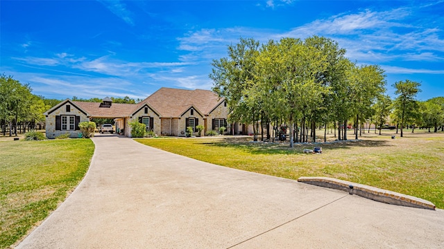 view of front of home with stone siding, concrete driveway, and a front yard