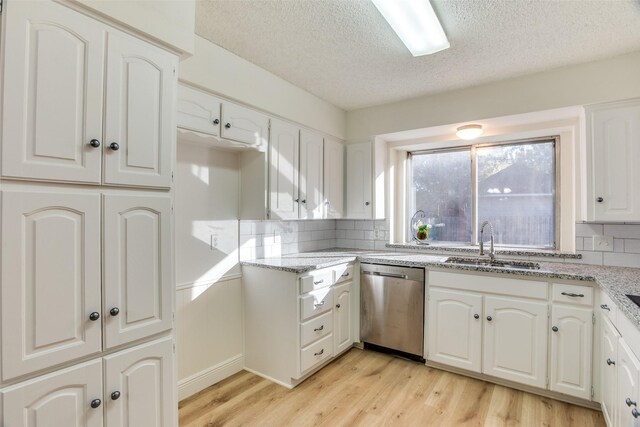 kitchen with white cabinetry, dishwasher, light hardwood / wood-style floors, and sink