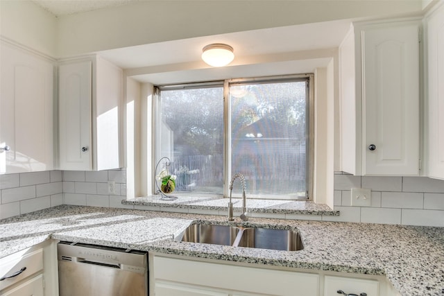 kitchen with light stone countertops, dishwasher, sink, tasteful backsplash, and white cabinets