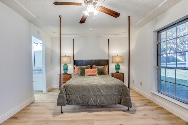 bedroom featuring a textured ceiling, light hardwood / wood-style floors, ensuite bath, and ceiling fan