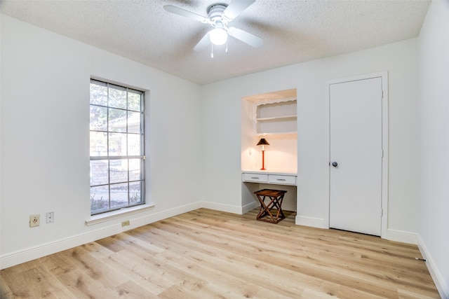 empty room with ceiling fan, a textured ceiling, and light wood-type flooring