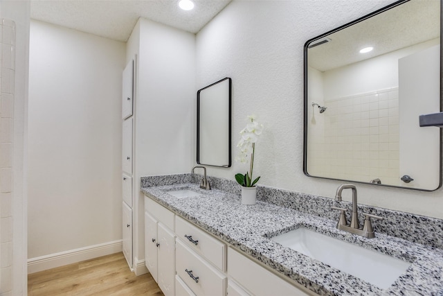 bathroom featuring tiled shower, wood-type flooring, vanity, and a textured ceiling