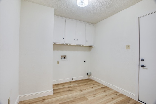 laundry area featuring hookup for an electric dryer, hookup for a washing machine, light wood-type flooring, cabinets, and a textured ceiling