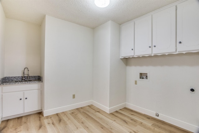 laundry room with sink, hookup for an electric dryer, hookup for a washing machine, light hardwood / wood-style floors, and a textured ceiling