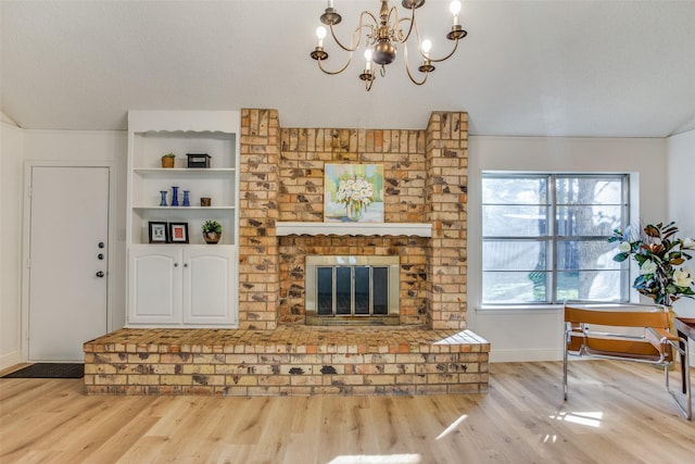 living room featuring lofted ceiling, a brick fireplace, light wood-type flooring, a textured ceiling, and a chandelier