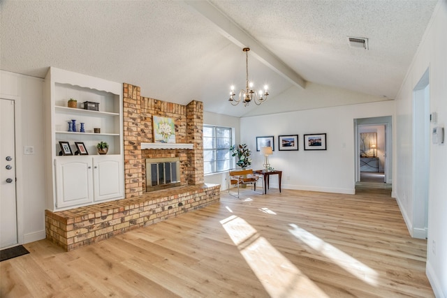 unfurnished living room with an inviting chandelier, lofted ceiling with beams, a textured ceiling, a fireplace, and light wood-type flooring