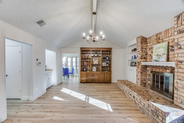 interior space featuring lofted ceiling, an inviting chandelier, a brick fireplace, light hardwood / wood-style flooring, and built in features