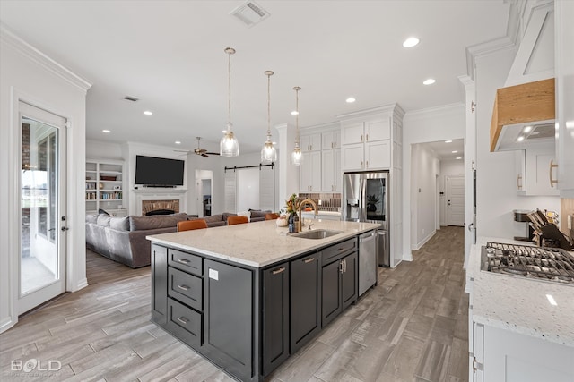 kitchen with ceiling fan, light stone counters, white cabinetry, and sink