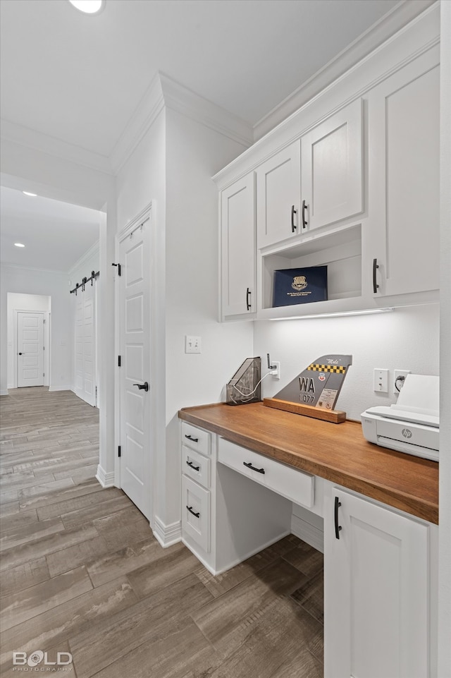 office with crown molding, built in desk, and hardwood / wood-style flooring