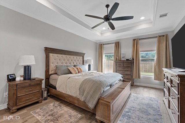 bedroom with light wood-type flooring, crown molding, a tray ceiling, and ceiling fan