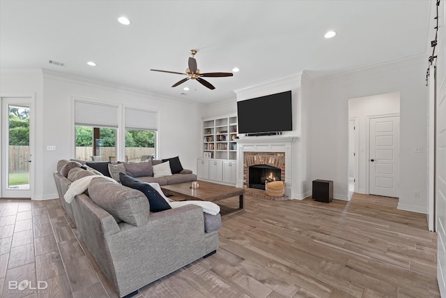 living room featuring light hardwood / wood-style floors, ornamental molding, ceiling fan, and a fireplace