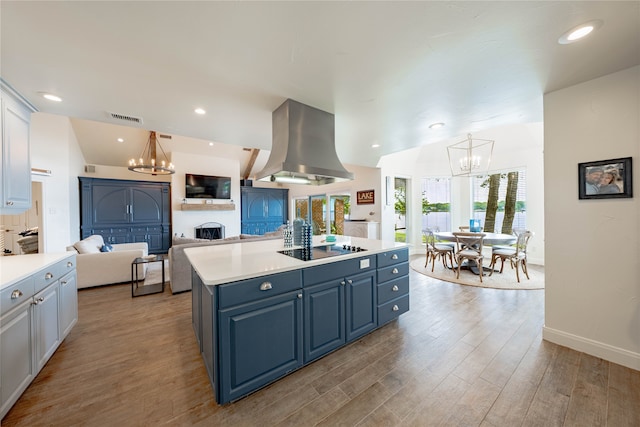 kitchen featuring an island with sink, island range hood, black electric cooktop, light wood-type flooring, and white cabinets