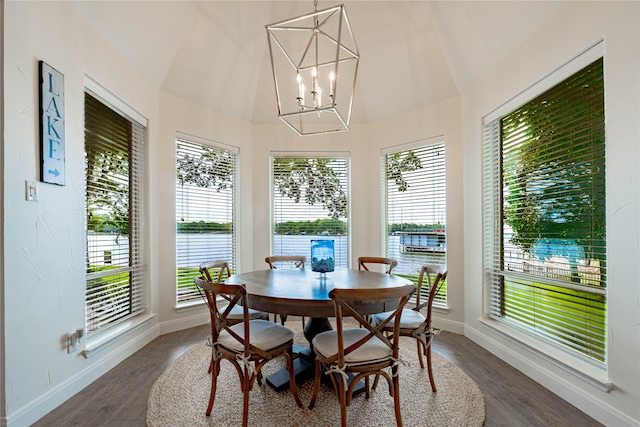 dining space featuring dark hardwood / wood-style flooring, a healthy amount of sunlight, a notable chandelier, and a water view