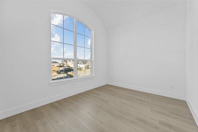 spare room featuring light hardwood / wood-style floors and lofted ceiling