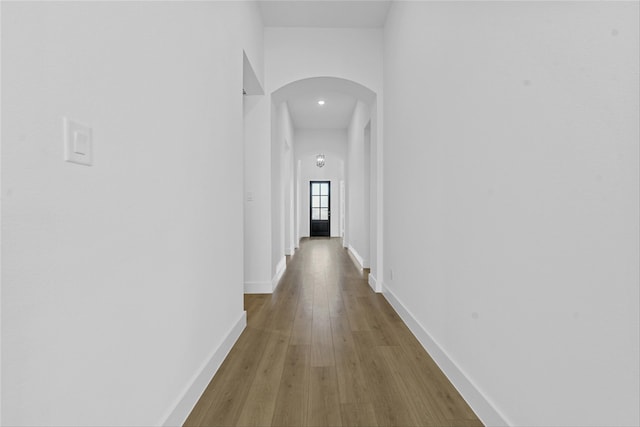 hallway featuring a towering ceiling and light hardwood / wood-style flooring