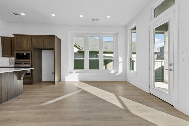 kitchen featuring light hardwood / wood-style floors, oven, dark brown cabinets, and built in microwave