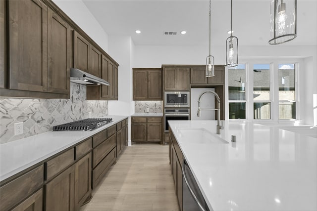 kitchen featuring sink, dark brown cabinets, pendant lighting, backsplash, and stainless steel appliances