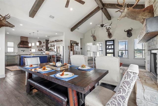 dining space featuring ceiling fan, a stone fireplace, vaulted ceiling, and wood-type flooring