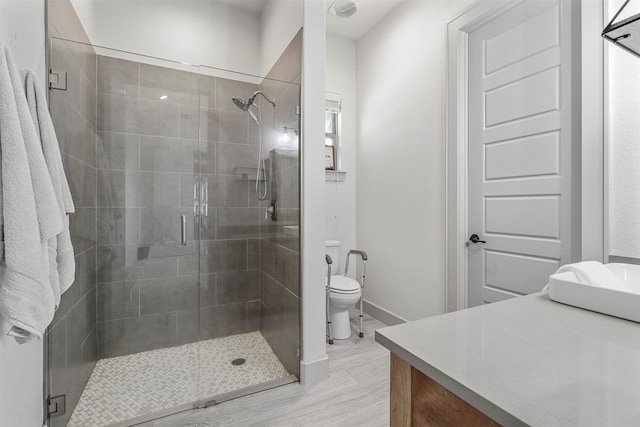 bathroom featuring a shower with door, toilet, and vanity