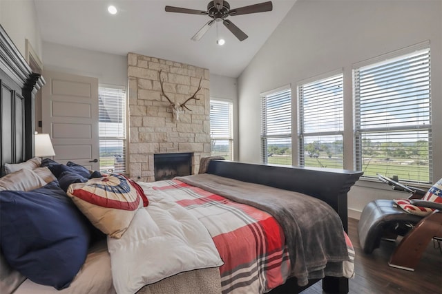 bedroom featuring ceiling fan, a fireplace, wood-type flooring, and lofted ceiling