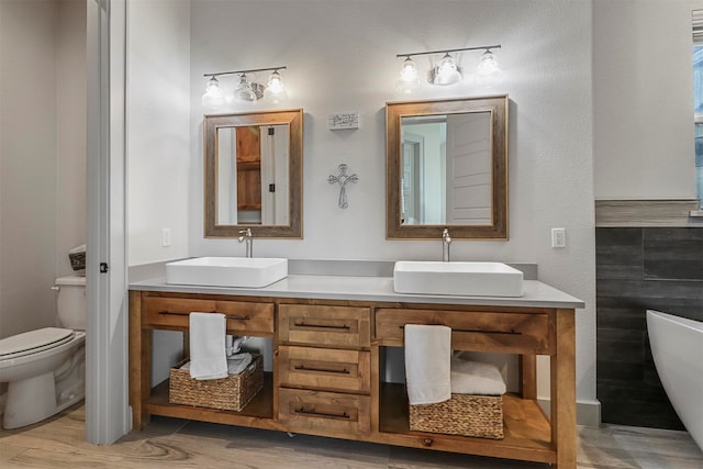 bathroom with a washtub, vanity, hardwood / wood-style floors, and toilet