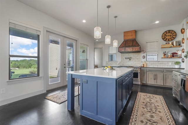 kitchen featuring decorative light fixtures, ventilation hood, tasteful backsplash, stove, and a center island