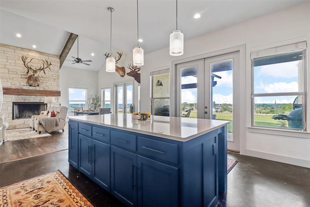 kitchen with blue cabinetry, a fireplace, a center island, ceiling fan, and hanging light fixtures