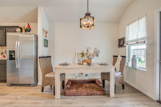 dining room featuring a chandelier, light hardwood / wood-style floors, and lofted ceiling