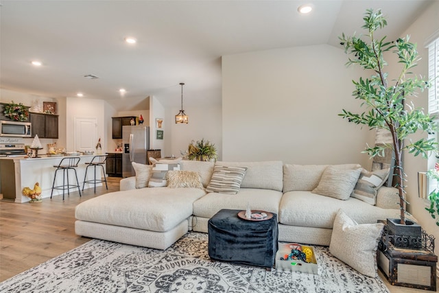 living room with light hardwood / wood-style floors and vaulted ceiling