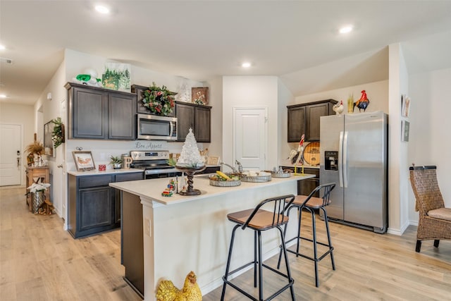 kitchen featuring a kitchen breakfast bar, light hardwood / wood-style flooring, a center island with sink, dark brown cabinets, and appliances with stainless steel finishes