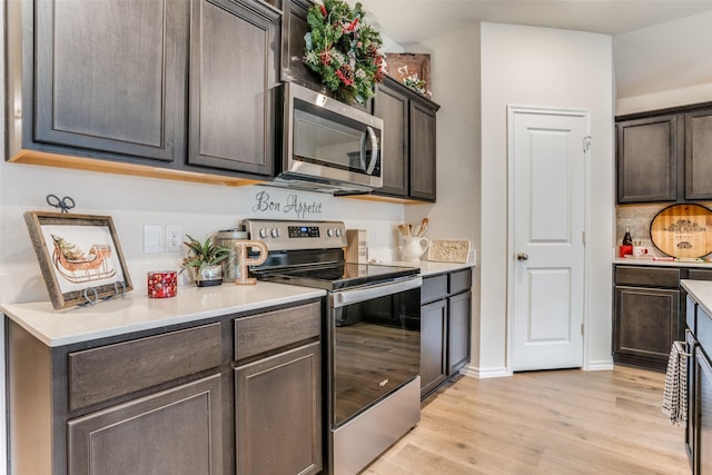 kitchen with dark brown cabinetry, stainless steel appliances, and light hardwood / wood-style floors