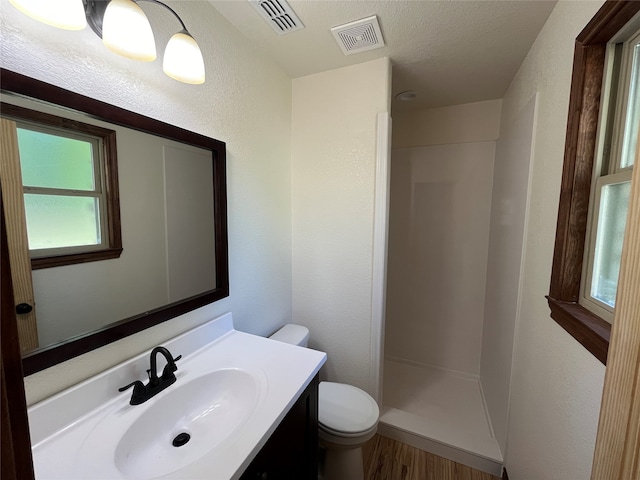 bathroom with hardwood / wood-style floors, a wealth of natural light, vanity, toilet, and walk in shower