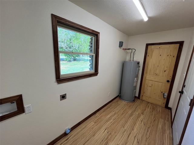 washroom with light wood-type flooring, a textured ceiling, water heater, and electric dryer hookup