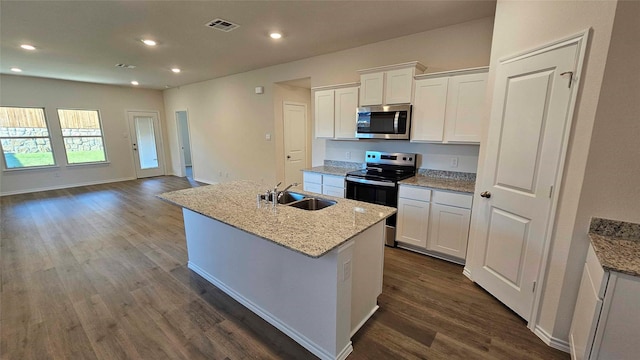 kitchen featuring sink, white cabinetry, light stone counters, a center island with sink, and stainless steel appliances