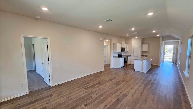 kitchen with stainless steel appliances, an island with sink, wood-type flooring, and white cabinetry