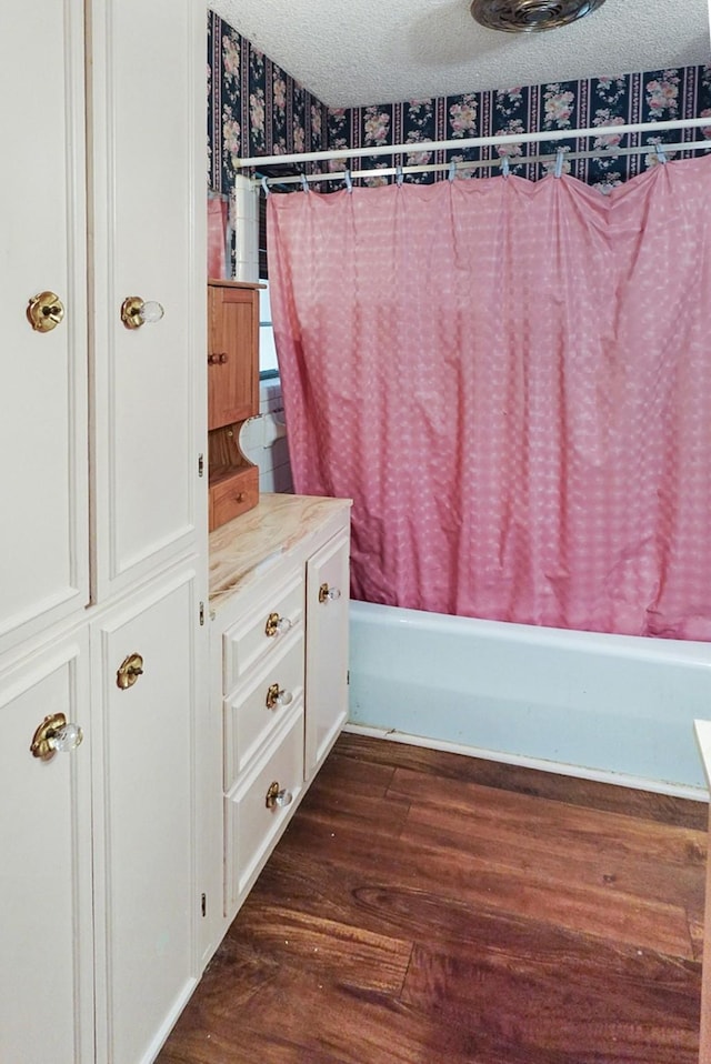 bathroom featuring wood-type flooring, a textured ceiling, and shower / bath combination with curtain