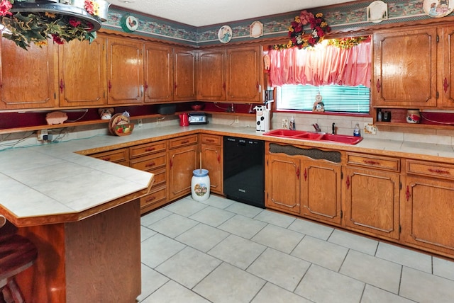 kitchen with tile counters, dishwasher, sink, kitchen peninsula, and light tile patterned flooring