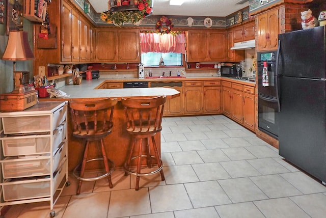 kitchen featuring black appliances, sink, light tile patterned flooring, kitchen peninsula, and a breakfast bar area