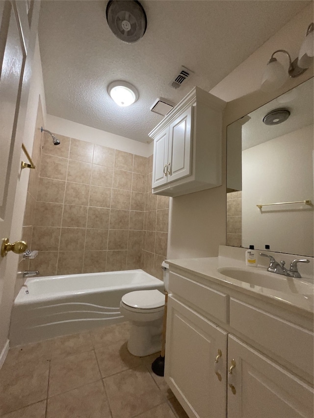 full bathroom with toilet, vanity, tile patterned floors, a textured ceiling, and tiled shower / bath combo