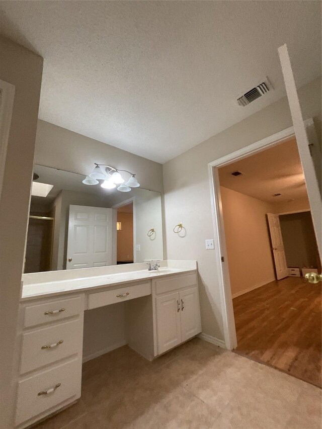 bathroom with a textured ceiling, vanity, walk in shower, and wood-type flooring