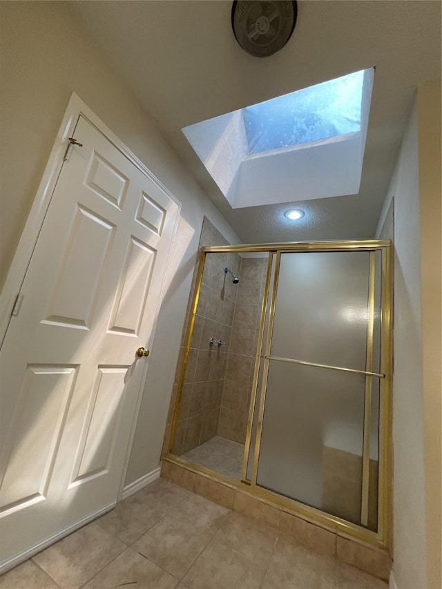 full bath featuring a stall shower, tile patterned floors, baseboards, and a skylight