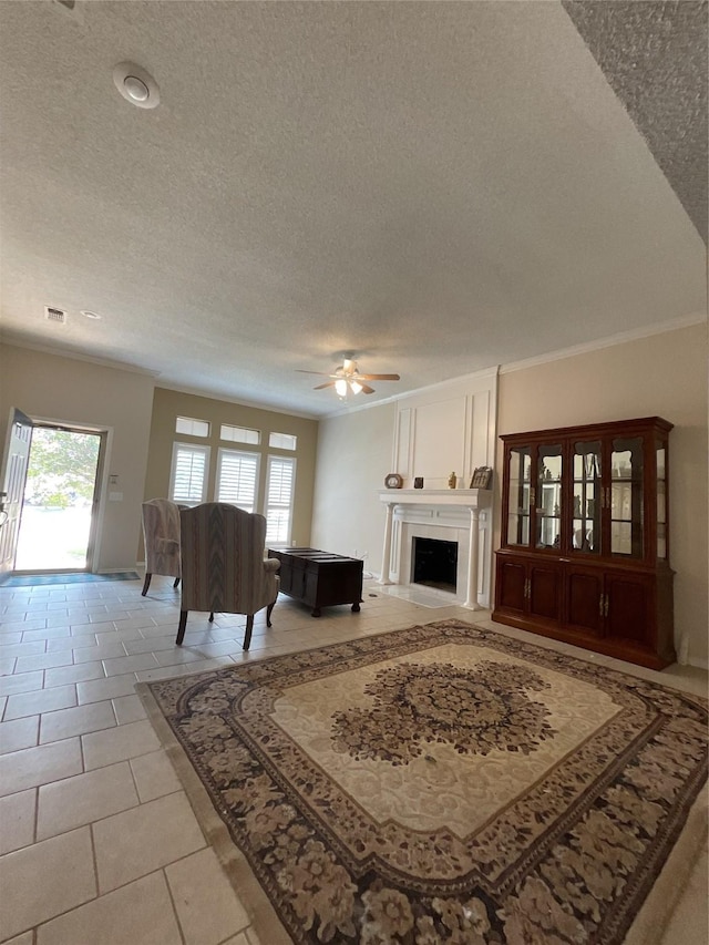 living room with light tile patterned floors, a large fireplace, ceiling fan, a textured ceiling, and baseboards