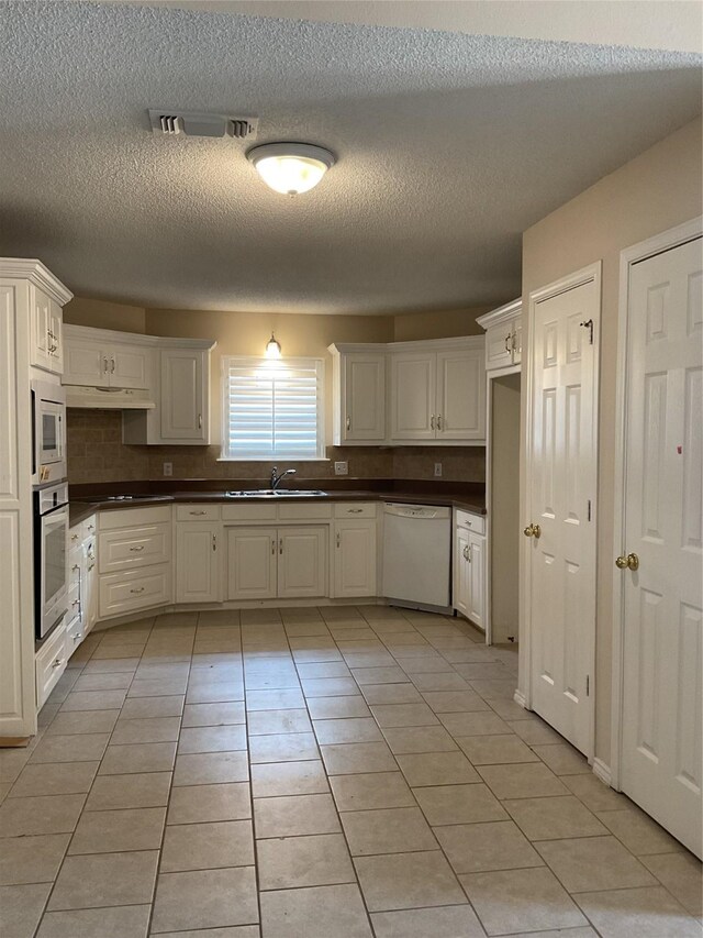 kitchen with appliances with stainless steel finishes, a textured ceiling, light tile patterned floors, and white cabinetry