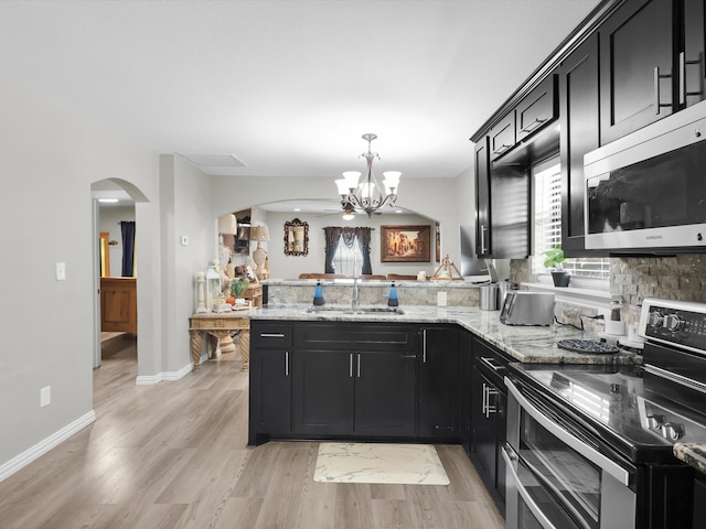 kitchen featuring light hardwood / wood-style floors, kitchen peninsula, stainless steel appliances, sink, and a notable chandelier