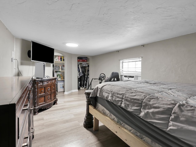 bedroom with cooling unit and light hardwood / wood-style flooring