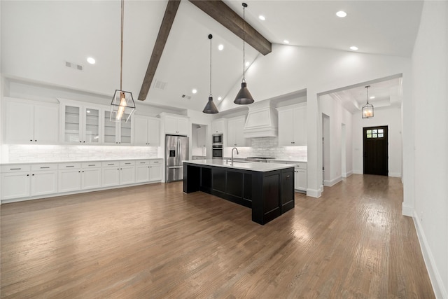 kitchen featuring decorative light fixtures, white cabinetry, an island with sink, and tasteful backsplash