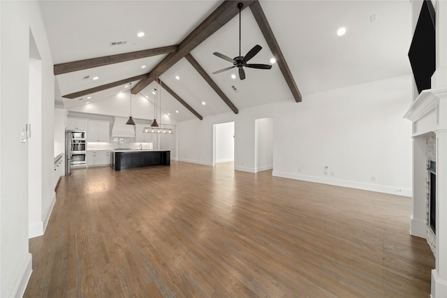 unfurnished living room featuring high vaulted ceiling, ceiling fan, a premium fireplace, beam ceiling, and wood-type flooring